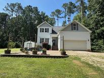 Charming two-story home featuring a well-manicured lawn, a two-car garage, and mature trees at 143 Rawhide Dr, Louisburg, NC 27549