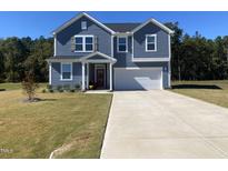 Charming two-story home with blue siding, red front door, well-kept lawn, and a two-car garage at 316 Robert Howe Dr, Fuquay Varina, NC 27526