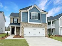 Charming two-story home boasts a blend of blue siding and brick, complemented by a pristine two-car garage and manicured lawn at 87 Nimble Way # 187, Clayton, NC 27520