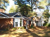 Charming brick home featuring arched windows and a welcoming entrance with elegant white pillars, creating a classic curb appeal at 6349 Elevation Rd, Benson, NC 27504