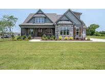 Charming home features a covered porch, manicured lawn, and stone accents, with a welcoming entrance at 20 Water Willow Ln, Zebulon, NC 27597