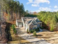 Aerial view of the home featuring a long driveway, mature trees and 3-car garage at 181 Colonial Ridge Dr, Pittsboro, NC 27312