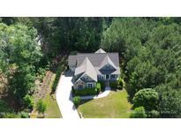 Aerial view of a two-story home with a long driveway and beautifully landscaped yard surrounded by lush trees at 181 Colonial Ridge Dr, Pittsboro, NC 27312