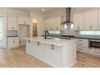 Bright kitchen features white cabinets, stainless steel appliances, and large center island with a black faucet at 103 Brandy Ml, Pittsboro, NC 27312