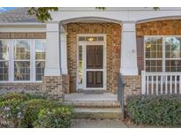 Welcoming front entrance with brick and stone accents, complemented by white pillars and lush landscaping at 719 Allforth Pl, Cary, NC 27519