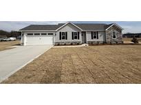 Charming single-story home with gray siding, stone accents, and a two-car garage on a sunny day at 102 Ruskin Dr, Smithfield, NC 27577
