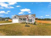 Charming single-Gathering home with a manicured lawn, gray siding, and an attached two-car garage at 128 Santa Rosa Way, Four Oaks, NC 27524