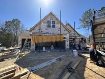 Unfinished new construction featuring a garage with workers and a blue sky backdrop at 104 Roma Gora Ct, Princeton, NC 27569