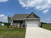 Charming single-story home featuring stone accents, a two-car garage, and a welcoming front porch at 11360 International Dr, Middlesex, NC 27557