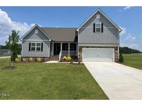 Charming two-story home with gray siding, stone accents, and well-manicured front lawn at 11376 International Dr, Middlesex, NC 27557