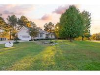 Charming home with a beautiful, well-manicured lawn and mature trees at sunset at 185 Franklin Ln, Henderson, NC 27537