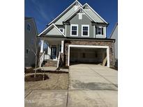 Charming two-story home featuring a stone facade, open garage, and well-manicured lawn at 2464 Field Poppy Dr # 168, Apex, NC 27502
