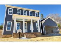 Two-story home boasting a charming brick-lined front porch and attached garage at 6044 Scalybark Road, Durham, NC 27712