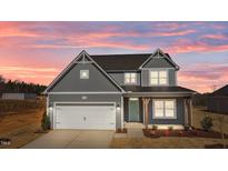 Charming two-story home featuring gray siding, a two-car garage, and a welcoming teal front door at 585 Husketh Rd, Youngsville, NC 27596