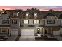 Two-story townhome with gray siding, white garage doors, and a charming front porch at 811 Pryor St, Mebane, NC 27302