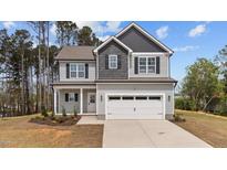 Charming two-story home featuring a two-car garage, landscaped yard, and inviting covered porch at 60 Bennett Rd, Coats, NC 27521