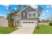 Charming two-story home with a well-manicured lawn, a two-car garage, and a mix of gray and light gray siding at 60 Bennett Rd, Coats, NC 27521