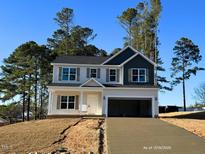 Charming two-story home features an attached garage, neutral siding and trim, and well-manicured landscaping at 78 Bennett Rd, Coats, NC 27521