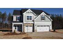 Beautiful two-story home with stone accents, gray siding, attached two-car garage, and professionally landscaped yard at 55 Accord Dr, Youngsville, NC 27596