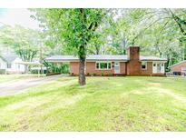 Charming brick home with well-kept lawn, carport, and a brick chimney, nestled among mature trees at 710 Spring Ln, Sanford, NC 27330