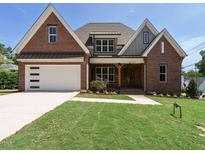 Beautiful brick home featuring a manicured lawn, a two-car garage, and a welcoming front porch at 2502 St Marys St, Raleigh, NC 27609