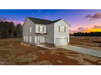 Two-story home with vinyl siding, attached garage, and new landscaping under a colorful sunset at 9154 Phoenix Ct, Spring Hope, NC 27882