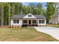 Charming single-story home with a welcoming front porch, black shutters, and manicured lawn at 200 Rawhide Dr, Louisburg, NC 27549