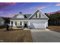 Beautiful single-Gathering home with a large two-car garage and covered front porch under a colorful sky at 91 Laramie Ln, Selma, NC 27576