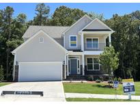 Charming two-story home with a manicured lawn, attached garage, stone accents, and covered porch at 113 Arundel Dr, Archer Lodge, NC 27527