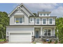 Beautiful two-story home with a light gray exterior, a covered front porch and an attached two-car garage at 115 Arundel Dr, Archer Lodge, NC 27527
