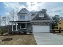 New two-story home featuring stone accents, gray siding, well manicured lawn and an attached two car garage at 116 Arundel Dr, Archer Lodge, NC 27527