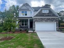 Beautiful two-story home featuring a stone facade, a two-car garage, landscaped yard, and a covered front porch at 116 Arundel Dr, Archer Lodge, NC 27527