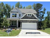 Charming two-story home featuring a stone facade, white siding, and an attached two-car garage at 116 Arundel Dr, Archer Lodge, NC 27527