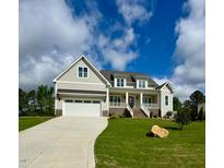 Charming two-story home with attached garage and inviting front porch under a sunny, partly cloudy sky at 1233 Azalea Garden Cir, Raleigh, NC 27603