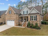 Charming brick home with a two-car garage, covered porch, and landscaped yard at 184 Dereham Ln, Garner, NC 27529