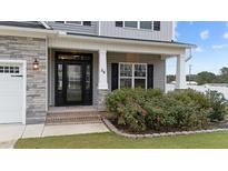 Two-story home with gray siding, stone accents, and a covered porch at 38 Locomotive Way, Clayton, NC 27520