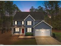 Charming two-story home with a manicured lawn, two-car garage, and inviting red front door at 5600 Thornburg Dr, Wake Forest, NC 27587
