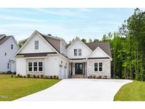 Beautiful two-story home featuring white siding, stone accents, and a well-manicured lawn at 617 Darian Woods Dr, Holly Springs, NC 27540
