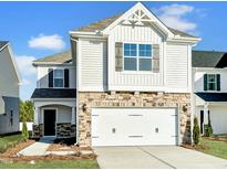 Charming two-story home featuring a stone facade, white siding, and an attached two-car garage at 63 Nimble Way # 183, Clayton, NC 27520