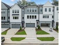 Modern townhome featuring gray and white facade, drive-under garages, and manicured landscaping at 4505 Mint Leaf Ln, Raleigh, NC 27612