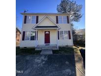 Two-story house with light yellow siding, red door, and small front yard at 2907 S Roxboro St, Durham, NC 27707