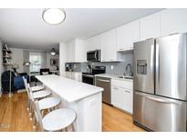 Modern kitchen features stainless steel appliances, white cabinets, and a breakfast bar that opens into the living area at 1320 S State Street # D, Raleigh, NC 27610