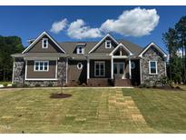 Beautiful single-story home boasting stone and brown plank siding with a well-manicured front lawn at 142 Batten Hill Ln, Selma, NC 27576