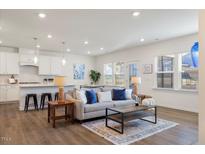 Bright living room featuring an open floor plan with modern furnishings and an adjacent kitchen area at 504 Morning Glade St, Wake Forest, NC 27587