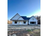 Charming single-story home with light gray siding, a covered front porch with columns and an attached two car garage at 6270 River Rd, Fuquay Varina, NC 27526