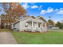 Charming single-story home boasts gray siding, white trim, inviting front porch and well-manicured lawn and mature landscaping at 923 Belvedere St, Rocky Mount, NC 27803