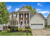 Two-story home featuring a brick front, white siding, a well-kept lawn, and an attached two-car garage at 3236 Forest Mill Cir, Raleigh, NC 27616