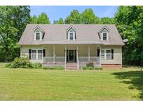 Inviting home with a charming front porch, manicured lawn, dormer windows and mature trees at 7039 Old 421 Rd, Liberty, NC 27298