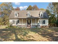 Charming home featuring a welcoming front porch, dormer windows and mature trees at 7039 Old 421 Rd, Liberty, NC 27298