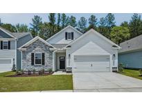 Charming home featuring stone accents, white siding, a two-car garage, and well-manicured lawn at 7529 Percussion Dr, Apex, NC 27539
